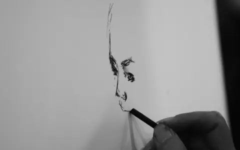 Dłoń artysty tworzy portret węglem. Każda prosta kreska buduje twarz, uchwyconą w momencie tworzenia.