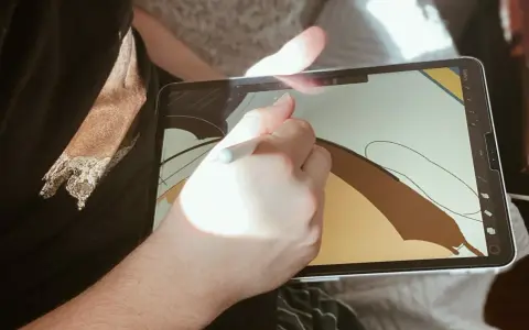 Osoba rysuje na ekranie iPad'a, używając rysika. To cyfrowy tablet graficzny, idealny do tworzenia sztuki.